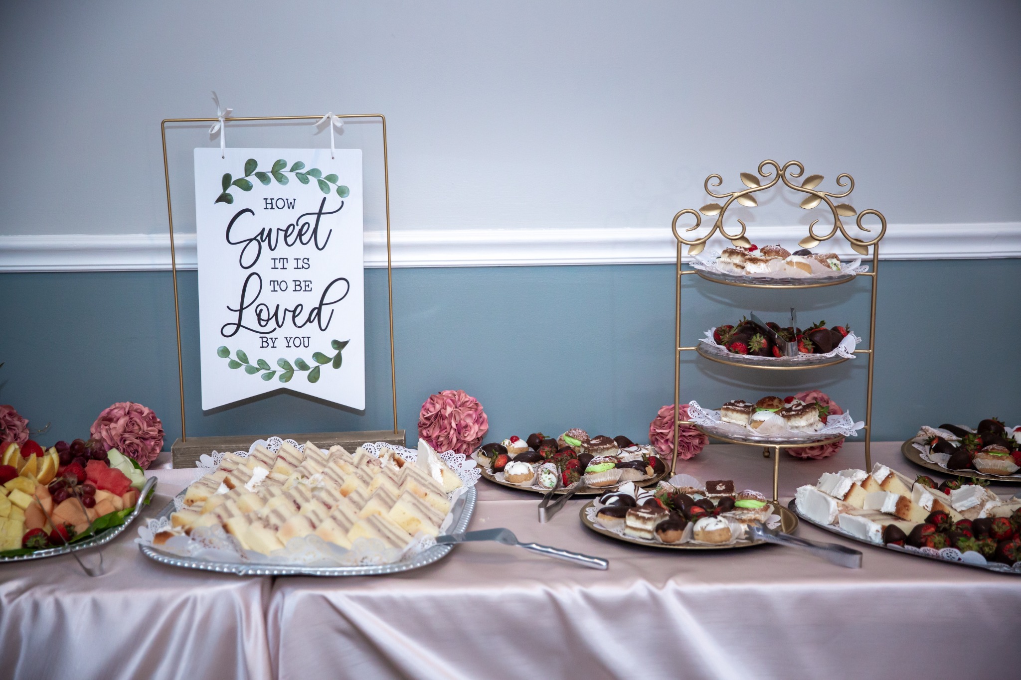 Wedding dessert table with cookies, pastries, fruit, and a decorative sign